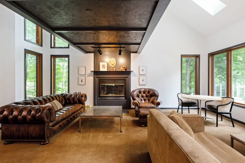 Gather in the inviting living room w/ rich leather seating, warm fireplace & soaring ceilings framed by tall windows.