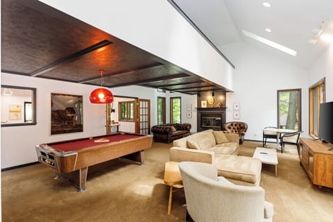 Step into luxury and leisure in this chic living room. With its airy space, natural light, and classic red-felt pool table, it's an invitation to unwind in style.