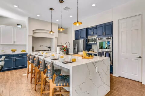 Gourmet kitchen with bold cabinetry, modern appliances, and seating for six at the oversized island.