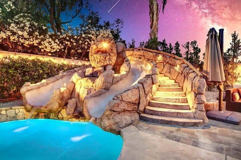Enjoy thrilling rides down this custom-built waterslide nestled beside the glowing evening poolscape.