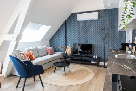 A cozy living room with a contemporary blue sofa and matching decor, set against a patterned wall, ideal for relaxing or entertaining guests.