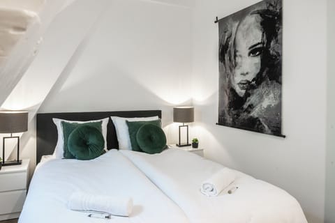 A cozy bedroom with a comfortable bed, soft pillows, and an artful portrait on the wall, creating a relaxing space.