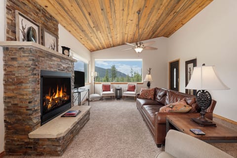 - Living room with stone fireplace and leather sofa   - Large windows frame scenic Rocky Mountain views   - Cozy cabin space for relaxing after outdoor fun