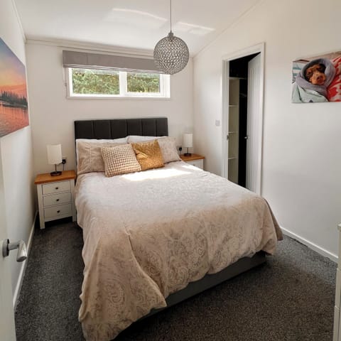 The double bedroom features a tranquil atmosphere with bedside tables and lamps on either side of the bed. A spacious walk-in wardrobe offers shelving and hanging space for convenient storage.