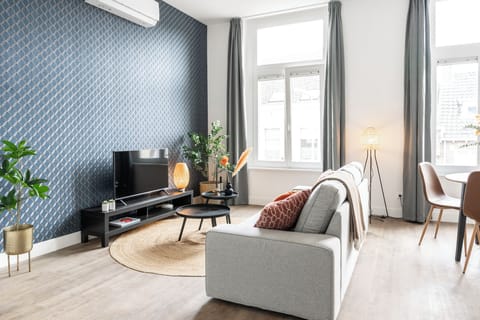 Spacious studio appartement Tilburg with a stylish sofa, TV, dining area, and blue accent wall. Ideal for Bed en Koffie and goedkoop stays near Tilburg Centrum or Beekse Bergen.