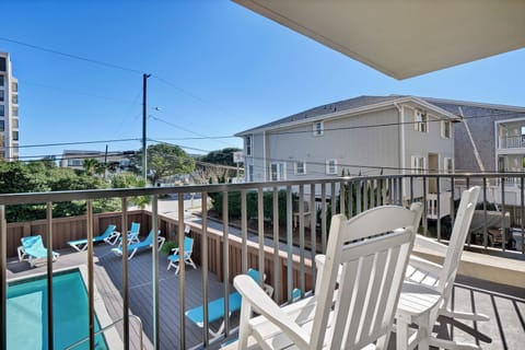 Enjoy your morning coffee on this private balcony overlooking the sparkling pool below, where white Adirondack chairs await sunny afternoons.