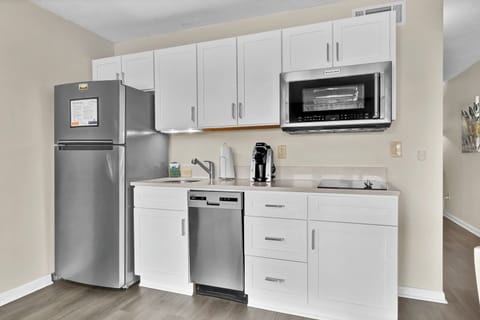 Your fully equipped kitchenette features modern stainless steel appliances and sleek white cabinetry, perfect for preparing light meals during your stay.