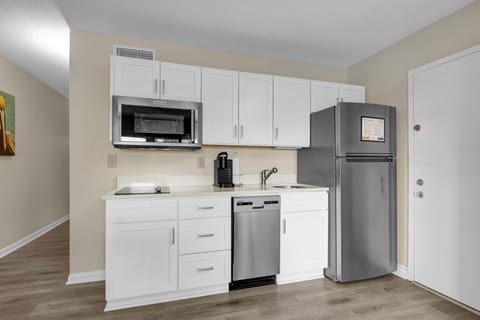 Your modern kitchenette features white cabinetry and stainless steel appliances, including a dishwasher, microwave, and full-size refrigerator for all your culinary needs.