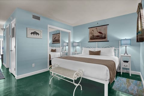 Drift off to sleep in this serene bedroom with coastal charm, featuring vintage bird artwork and calming blue walls.