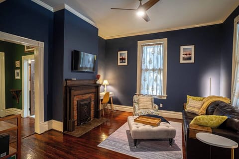 The living room has a lovely fireplace, a separate desk, a sleeper couch, and historic details.