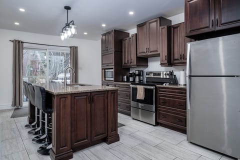 Modern executive kitchen with seating for four additional guests, complemented by a dining table that accommodates eight. Glass patio doors in the kitchen provide access to the back patio and large backyard.