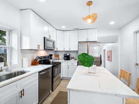 Sleek kitchen with stainless steel appliances and bright white cabinets - Spacious island with bar seating perfect for group dining - Fully equipped Airbnb kitchen ideal for extended stays