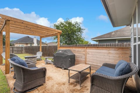 Custom arbor with outdoor firepit and Adirondack chairs and grill 