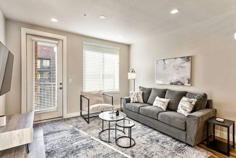 Bright living room w/ cozy sofa seating, wall art & large windows bringing in soft natural light