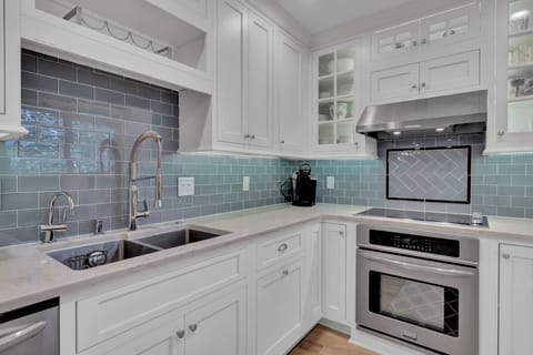 - Cook in style with sleek appliances, glass front cabinets, and a deep farmhouse sink - Soft gray blue backsplash adds a splash of personality to this clean, upscale kitchen - Whether you’re making coffee or dinner, this space is a joy to use