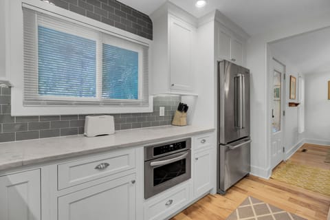 - Prep meals with ease on quartz counters, framed by sleek white cabinetry & stainless appliances - Large oven, full fridge, & custom backsplash bring function & flair - Natural light from the window adds a warm, welcoming glow to your morning routine