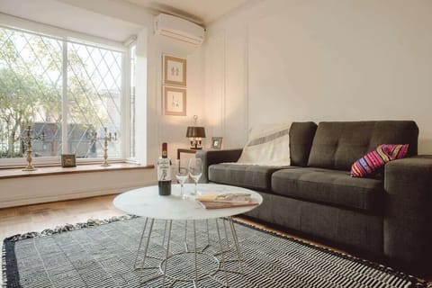 Relax in this stylish living room with a cozy sofa, natural light, and a perfect spot for a glass of wine.