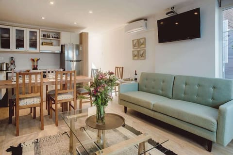 Bright and modern living space with a cozy sofa, stylish dining area, and fully equipped kitchen—perfect for relaxing and entertaining.