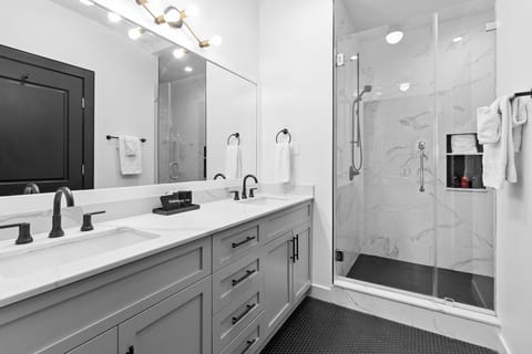 The primary bathroom offers sleek finishes, a soaking tub with Smart TV, walk-in shower, and plush towels. Spacious and private, it adds a luxurious touch to your suite—perfect for unwinding after a day in Downtown New Orleans.