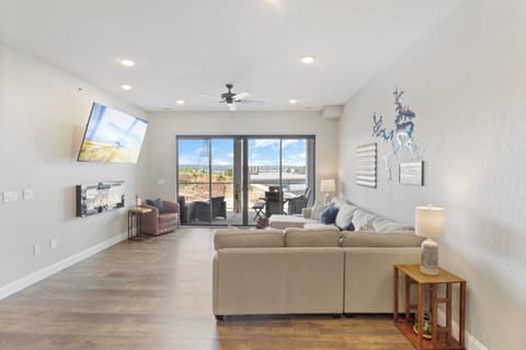 Bright and spacious living area featuring modern decor, a large flat-screen TV, and an electric fireplace.