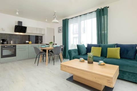 Living room with sofa, TV and kitchenette with dining area.