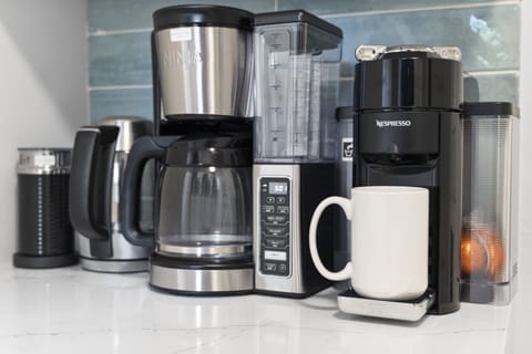 Fully equipped coffee station with tea kettle, milk frother, Nespresso machine with pods, and drip coffee maker-your morning routine, elevated.