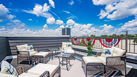 Experience the ultimate relaxation on a spacious rooftop deck with cozy lounge chairs and stunning views, perfect for sipping a drink as the sun sets over Arlington's entertainment district.