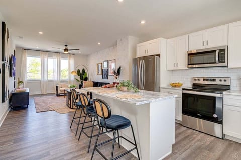 Open kitchen with stainless steel appliances, large island, breakfast bar seating, and is fully equipped with your basic cooking essentials.