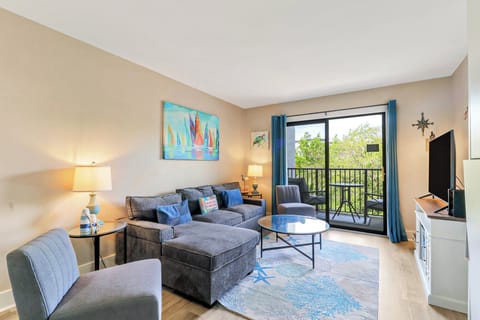 Ocean-inspired hues of cobalt and turquoise brighten this airy lounge, where plush seating and glass surfaces catch the afternoon glow. Open the broad glass door to let in a gentle breeze from the leafy balcony.