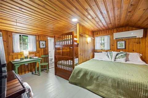 “Cozy room with King bed and green lining, twin bunk bed, green dining table for two.