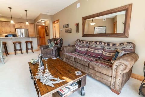 Relax in this modern open-concept living room featuring a plush sofa, smart TV, and large windows that fill the space with natural light.