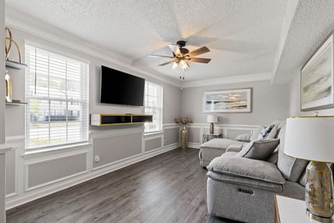 Relax in the plush living room with ample seating, a ceiling fan, and a Samsung Smart TV for all your entertainment needs.