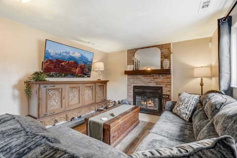 Photo 1: Cozy seating gathered around a fireplace and TV creates an easy place to unwind after a long day. Settle into the sofa, set drinks on the wood coffee table, and enjoy the warm glow from the lamp and fire for relaxed evenings in.