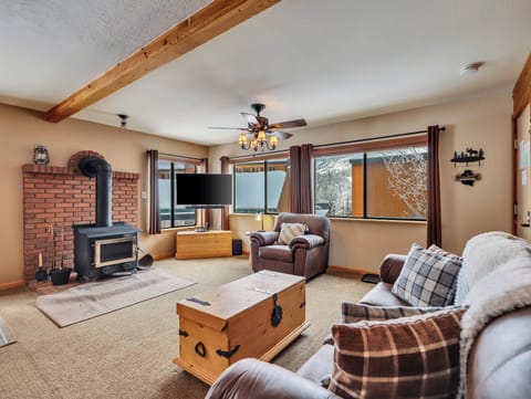 Cozy living room with a wood-burning stove, 55" smart TV, comfortable queen sleeper sofa, armchair, and ceiling fan for ultimate relaxation