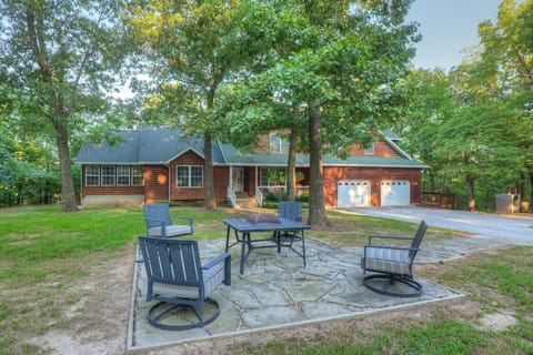Find peace and comfort in this lovely house, featuring a vast grassy area and a relaxing outdoor seating space amidst the trees.