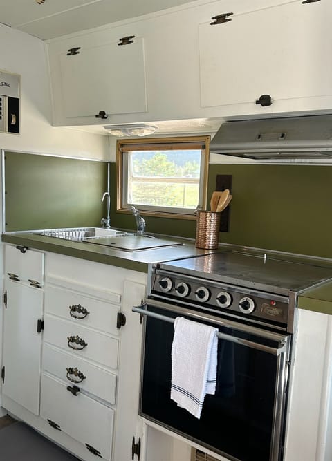 Featuring a stainless steel oven (not functional), stovetop, a double sink and ample storage.
