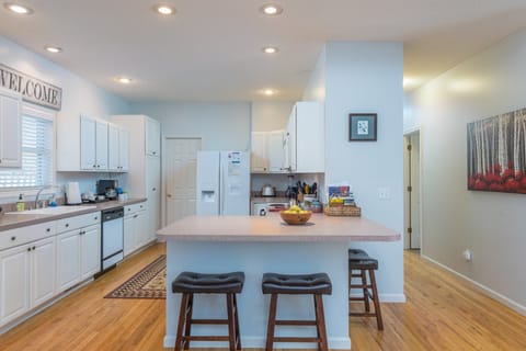 A well-appointed kitchen equipped with modern appliances, including a dishwasher and drip-style coffeemaker, along with an island that offers additional seating for three.
