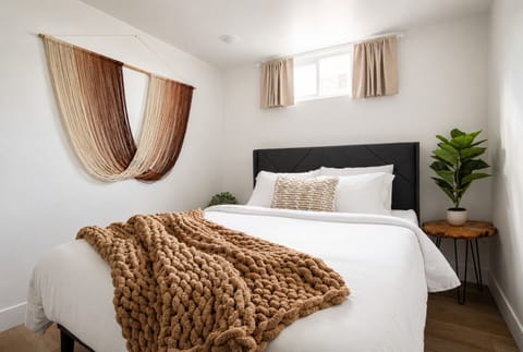 Cozy bedroom 1 with new queen bed, mirror, open clothes storage with hangers wit