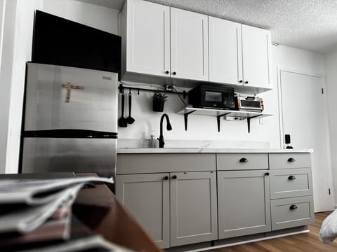 Fridge, induction cooktop, microwave, toaster, kettle, coffee, tea, utensils.