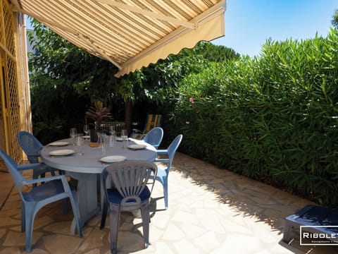 Shady garden with barbecue, sun loungers and dining table