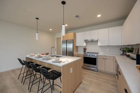 Unit 1: Fully equipped modern kitchen stocked with culinary essentials featuring stainless steel appliances with island bar seating.