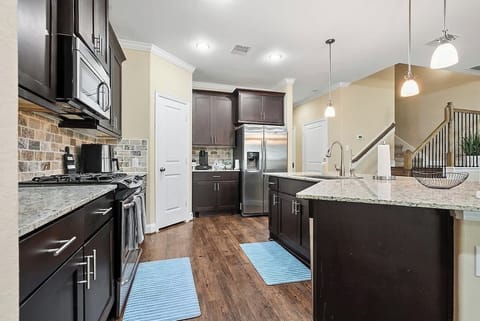 Indulge in culinary delights in our spacious and modern kitchen! Enjoy the sleek look of new stainless appliances. Stocked with pots, pans, dishes, and utensils, it's perfect for entertaining & bonding over meals. Cook your favorite foods with ease.