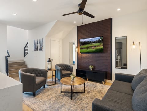 1st Floor: Warm and inviting living room featuring a Smart TV for entertainment, and designer furnishings including a sleeper sofa that converts into a Queen Bed.