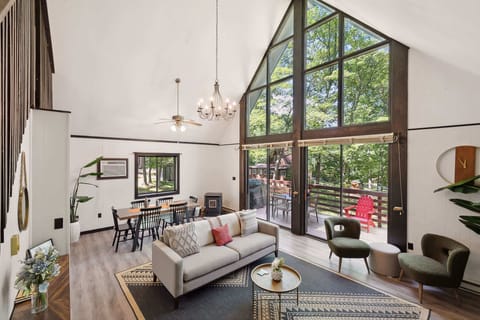 Spacious living area with vaulted ceilings and large windows overlooking the deck and trees.