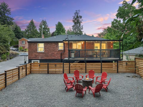 - Spacious fenced yard with red chairs and fire pit view  
- Watch sunsets from the deck with glowing string lights  
- Relaxed outdoor seating area ideal for gathering time  
