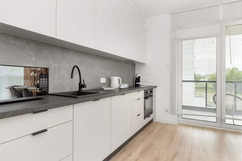 A bright kitchen with a large window provides a comfortable space for cooking, where natural light highlights the modern finishes.