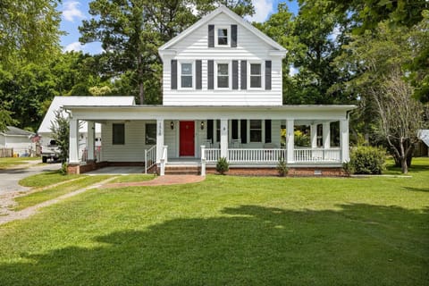Cozy farmhouse with a large porch and rocking chairs, nestled in the magnolias