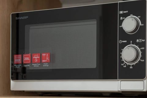 A close-up of a microwave oven with control knobs and safety stickers. Ready for quick meal prep or reheating snacks.