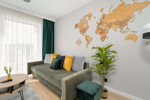 A cozy, modern living room with a couch, green curtains, and a world map decoration on the wall.