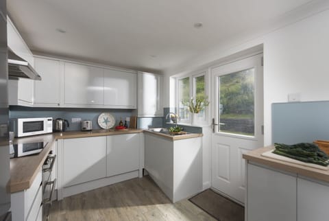 Castaways, Porthtowan. Ground Floor: The kitchen is well equipped with an electric oven and hob, microwave, fridge/freezer, dishwasher and washer/dryer